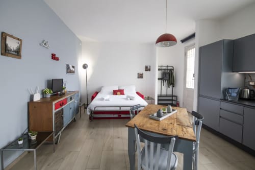 Modern studio apartment in Ferrara with red bed, dining table, kitchenette, and living area