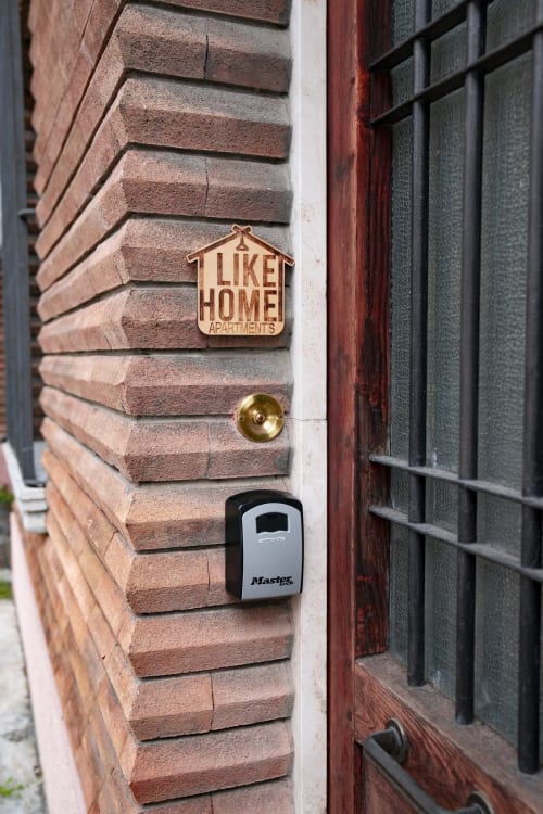 LikeHome Apartments entrance sign and Master Lock key box on brick wall in Ferrara, Italy