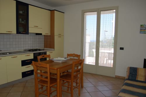 Luminosa cucina gialla con zona pranzo e porte vetrate con vista sul mare nell'appartamento di Santa Cesarea Terme