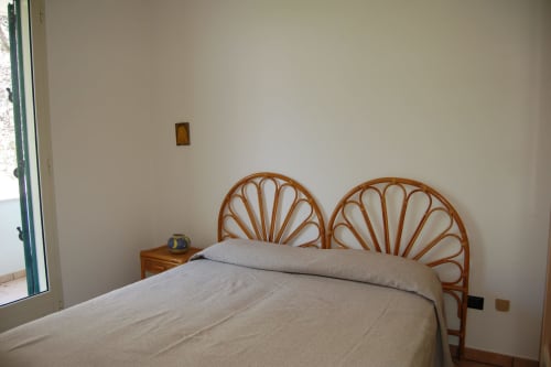Camera da letto con testata a ventaglio in legno e biancheria beige presso l'appartamento Santa Cesarea Vacanze, Italia