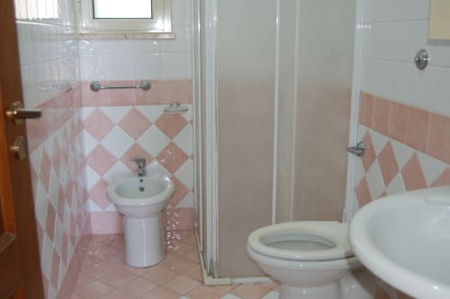 Bagno di Santa Cesarea Vacanze con piastrelle rosa e bianche a losanga, lavabo con piedistallo, WC e doccia in appartamento