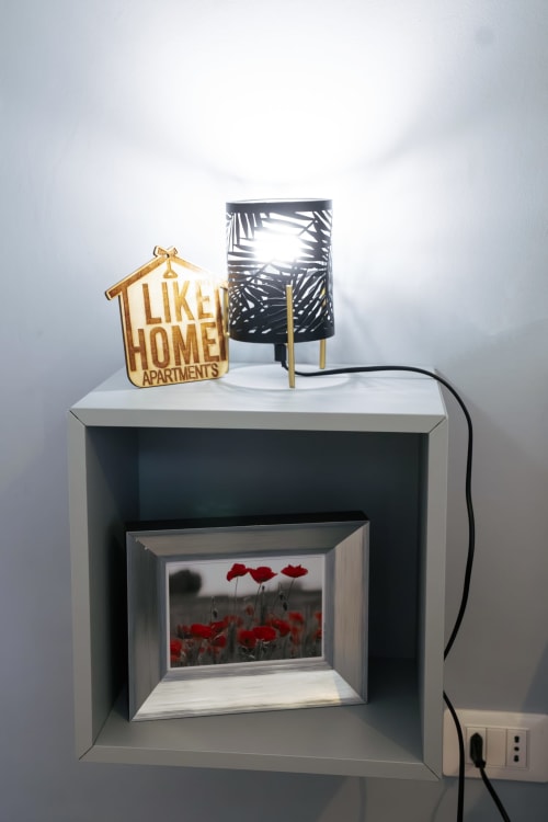 LikeHome Apartments Ferrara display shelf with welcome sign, decorative lamp, and framed poppy field photo