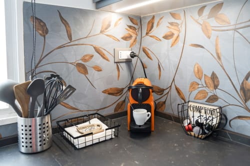 Kitchenette counter in Ferrara apartment with orange coffee machine, cooking utensils, and botanical leaf wallpaper