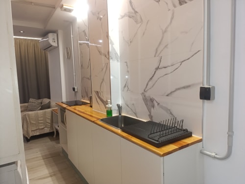 Baño moderno en apartamento El Rincón de Sevilla con tocador de madera, lavamanos negro, paredes de mármol y ducha