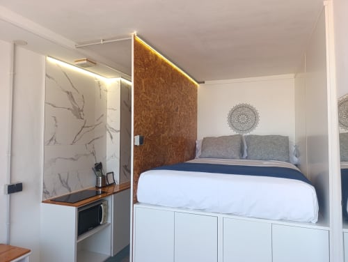 Alcoba moderna en apartamento El Rincón de Sevilla con cama elevada, cabecero de corcho, almacenamiento blanco y