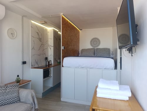 Apartamento estudio moderno en Sevilla con cama elevada, cocina americana, escritorio, sofá y TV mural cerca del metro