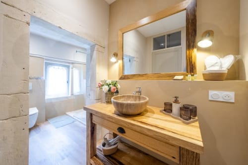 Modern bathroom with wooden sink vanity, round vessel sink, and mirror at Le Jardin Secret cottage in Grignan