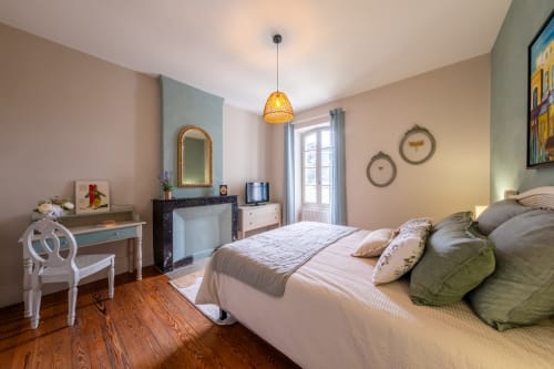 Elegant bedroom at Le Jardin Secret B&B in Grignan with queen bed, vanity, fireplace, and pool view