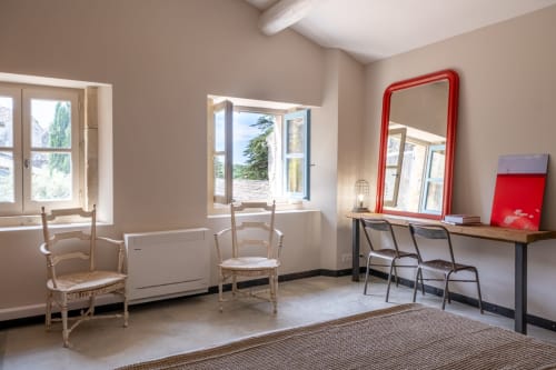 Bright cottage living room at Le Jardin Secret with red mirror, wooden chairs, desk, windows overlooking pool area