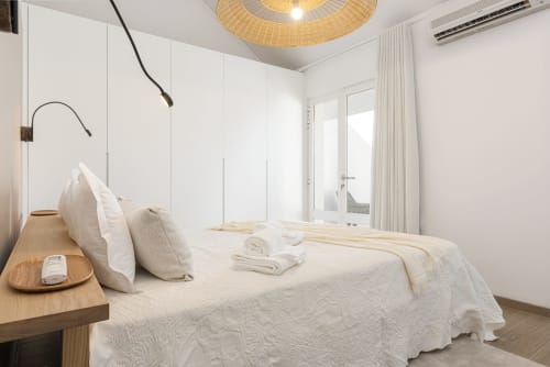 Quarto moderno no RB Algarve CATCH Vilamoura com roupa de cama branca, criado de madeira, decoração minimalista e vistas da cidade