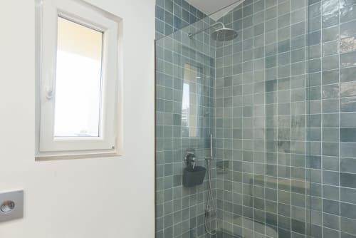 Banheiro moderno com azulejos verdes e chuveiro tipo chuva no apartamento CATCH, Vilamoura, hotel RB Algarve