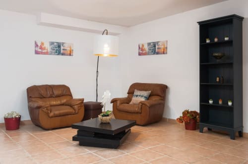 Sala de estar moderna na villa JUDY, RB Algarve, com poltronas de couro bege, estante preta e lareira.