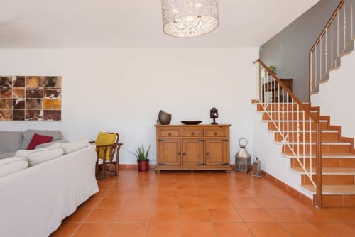 Sala de estar de villa moderna com pisos em terracota, escada de madeira e móveis contemporâneos na RB Algarve