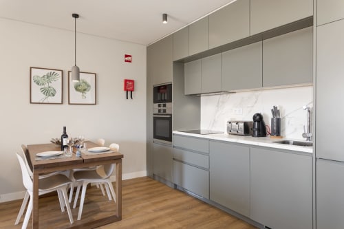 Cozinha e sala de jantar modernas no apartamento MILA no RB Algarve, Vilamoura, com móveis cinzentos, backsplash em mármore e madeira