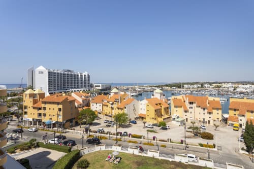 Hotel RB Algarve em Vilamoura, Portugal com edifícios residenciais amarelos, marina e moderna torre hoteleira com vista para o
