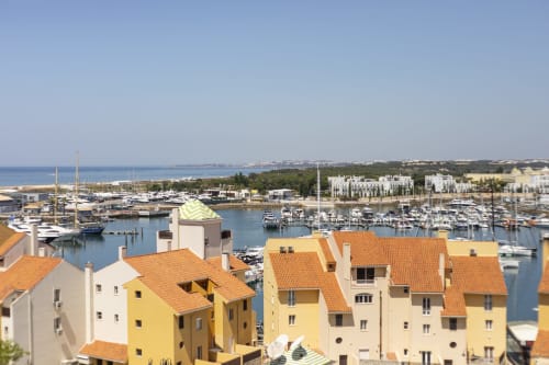 Edifícios coloridos com vista para a marina de Vilamoura em Portugal, com barcos e vistas da costa