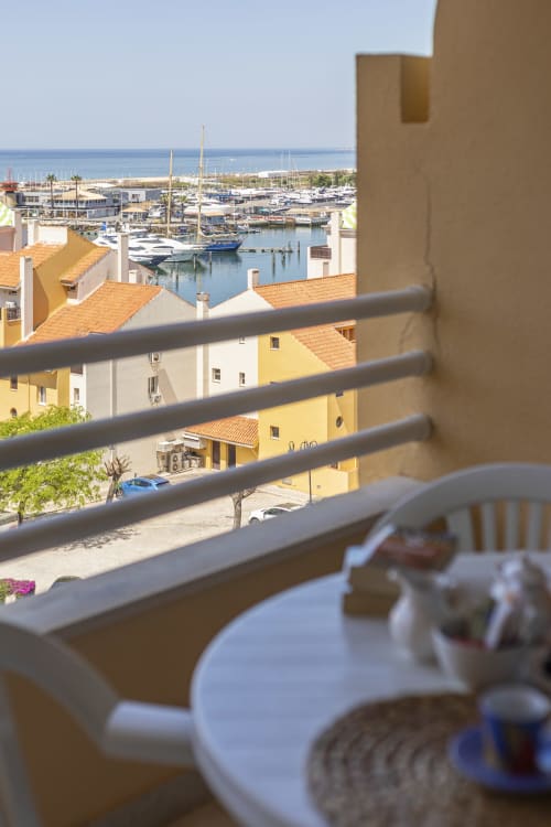 Vista da varanda com marina, edifícios coloridos e veleiros no porto mediterrânico do apartamento RB Algarve Vilamoura