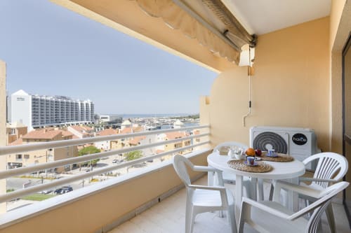 Varanda com vista mar no apartamento RB Algarve Vilamoura, com cadeiras brancas, mesa redonda e unidade de AC