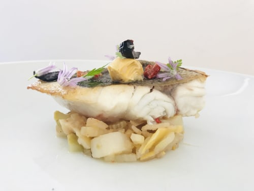 Filet de poisson gourmand à la peau croustillante sur frites dorées, garni de fleurs comestibles à la Maison Nolette