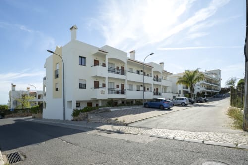 Hotel RB Algarve em Albufeira com apartamentos brancos, estacionamento e palmeiras sob céu azul
