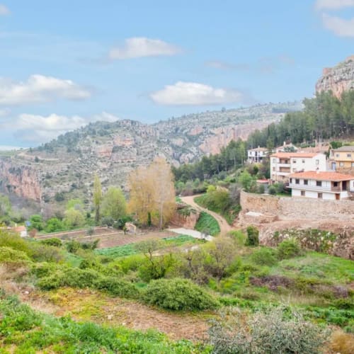Hotel Rustikalpuente en el campo español con edificios de terracota, olivos y paisaje de colinas rocosas