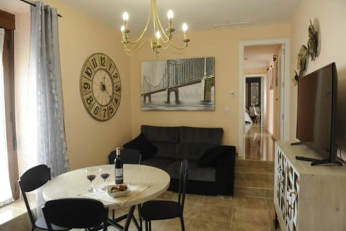 Modern living room with dining area at Complejo Turístico Retiro del Teatro, Almagro, featuring black sofa, round clock, and