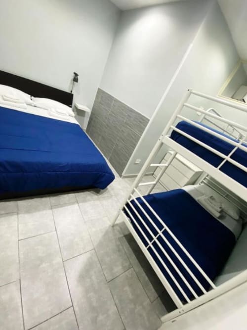 Dormitory room at Neapolis Tecnotourist BnB with blue-bedded bunk beds and tile flooring