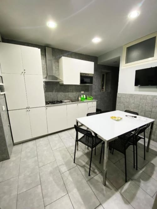 Modern kitchen dining area at Neapolis Tecnotourist with white cabinets, gray tiles, and black chairs