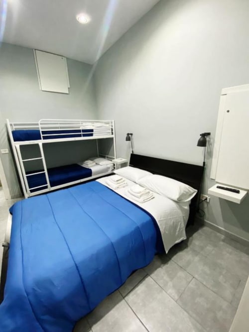 Modern bedroom at Neapolis Tecnotourist B&B with blue comforter, bunk bed, and black bed frame