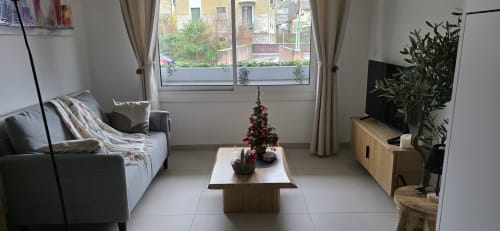 Salon moderne de l'hôtel Le 9 Victor Hugo à Aix-les-Bains avec canapé, table basse, télévision et vue sur la ville