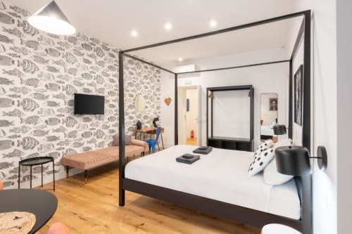 Modern bedroom at Suite Maradona BnB in Naples with canopy bed, fish-patterned wallpaper, and ensuite bathroom view