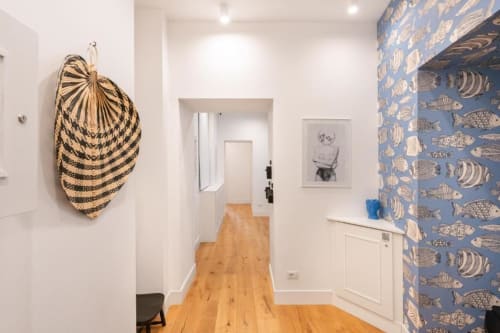Modern hallway at Suite Maradona Naples with woven basket art, fish wallpaper, and wooden floors