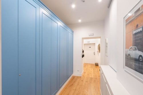 Modern hallway at Suite Maradona BnB in Naples with blue fitted wardrobes, wooden floors, and vintage car artwork
