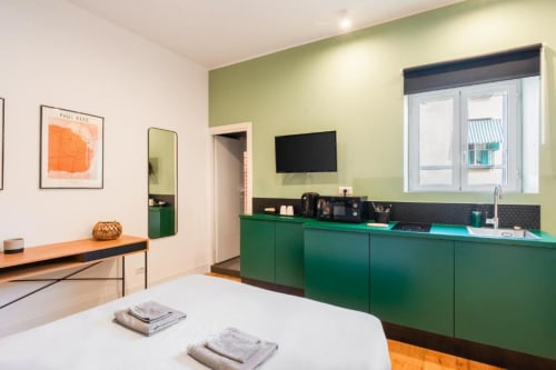 Modern Suite Maradona bedroom in Naples with green cabinetry, white bed, TV, and orange accent flooring