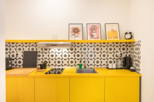 Bright yellow kitchen with black geometric backsplash at Suite Maradona, Naples Airbnb