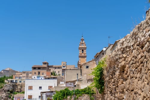 Pueblito mediterráneo histórico con edificios de piedra, campanario y cielo azul despejado en el hotel Rustikalpuente