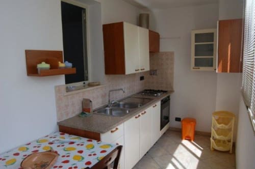 Cucina moderna con mobili bianchi, fornello a gas, lavello e pavimento colorato nell'appartamento Santa Cesarea Vacanze in Italia