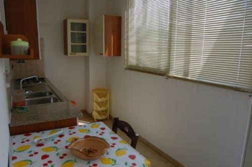 Area cucina dell'appartamento La Casetta a Santa Cesarea Vacanze con tavolo a motivi fruttati, lavello e finestre con vista