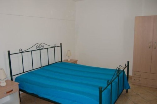 Camera da letto con letto in ferro battuto e biancheria blu presso l'appartamento Santa Cesarea Vacanze in Italia