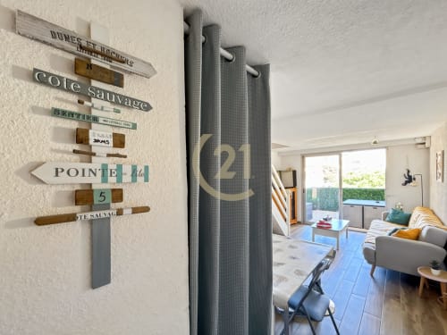 Entrée élégante d'un duplex moderne à L'Île-Rousse avec décoration murale côtière et vue sur le séjour par la porte