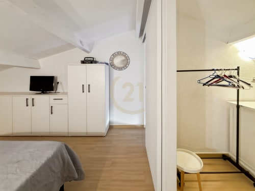 Chambre moderne de duplex à L'Île-Rousse avec mobilier blanc, TV, horloge, parquet et placard