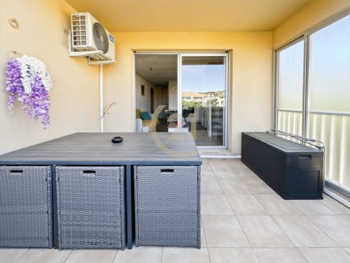 Terrasse de duplex moderne à L'Île-Rousse avec table à manger, rangements, bain à remous et vue sur la ville