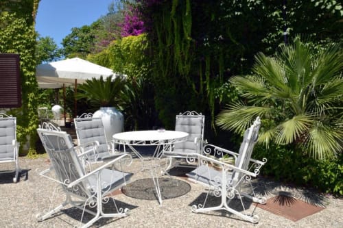 Elegant outdoor patio seating area at Mas Collection hotel in Bari with white wrought iron furniture and lush Mediterranean