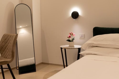 Modern bedroom at Mas Collection hotel in Bari with bed, mirror, nightstand and pink flowers