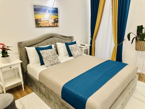 Elegante camera matrimoniale Deluxe presso St Mary Major Loft Roma, con letto rivestito in beige, accenti blu e vista della città