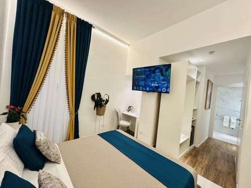 Moderna camera doppia lusso al St Mary Major Loft Roma con vista sulla città, TV a schermo piatto, tende blu e oro, e arredamento contemporaneo