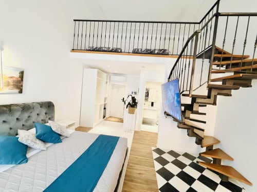 Camera da letto in stile loft moderno a Santa Maria Maggiore a Roma con letto king, scala in legno, TV a schermo piatto e vista sulla città