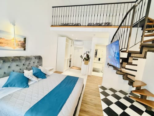 Suite Loft Superior St Mary Major a Roma con letto matrimoniale, dettagli blu, scala in legno, TV a schermo piatto e vista sulla città