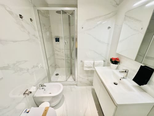 Bagno in marmo moderno al St Mary Major Loft Roma con doccia in vetro, bidet e vanity bianca con servizi