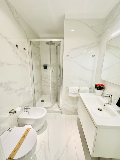 Bagno moderno in marmo al St Mary Major Loft Roma con doccia in vetro, doppio lavabo, toilette e asciugamani bianchi